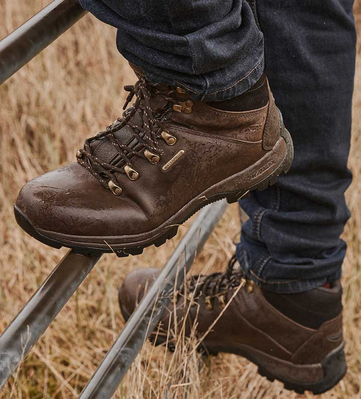 Walking and hiking boots. Brown leather lace up hiking boots climbing on a gate. 