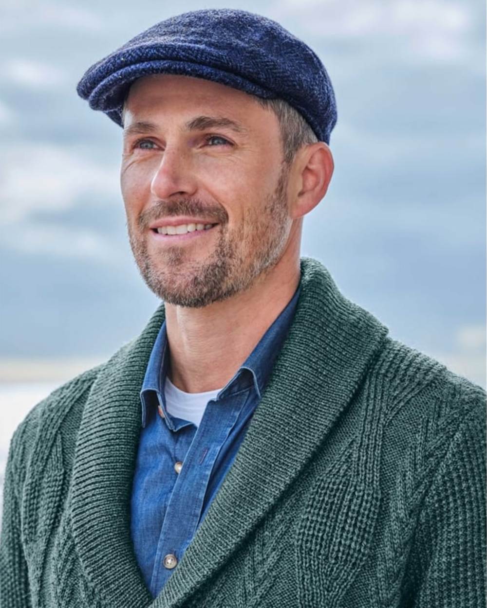 Navy Coloured Hoggs of Fife Herringbone Waterproof Tweed Flat Cap on sky background