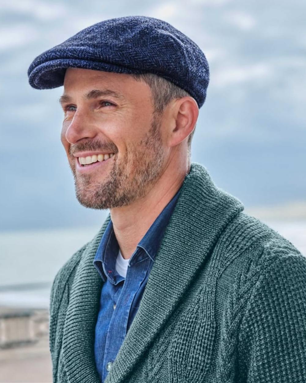 Navy Coloured Hoggs of Fife Herringbone Waterproof Tweed Flat Cap on sky background