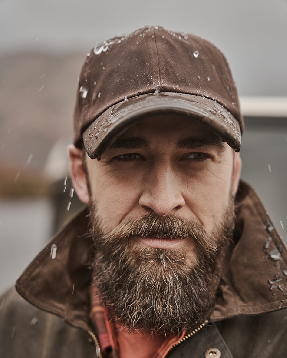 Brown Coloured Hoggs of Fife Leather Peak Waxed Baseball Cap on blurry background