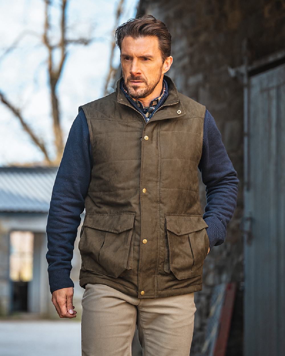 Loden coloured Hoggs of Fife Mens Glenbervie Quilted Gilet on house background