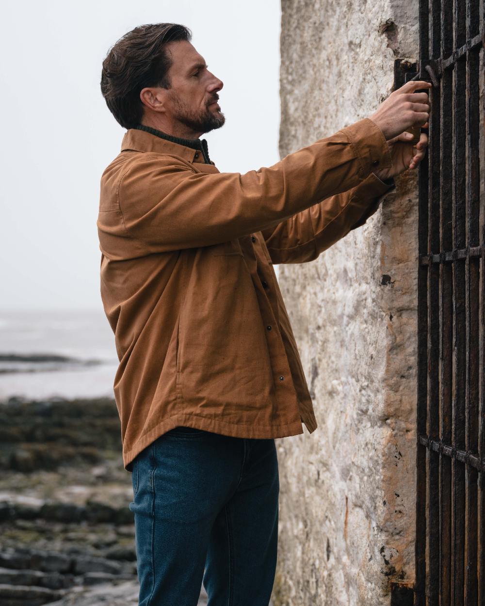 Caramel coloured Hoggs of Fife Mens Huntly Waxed Canvas Utility Overshirt on coastal background