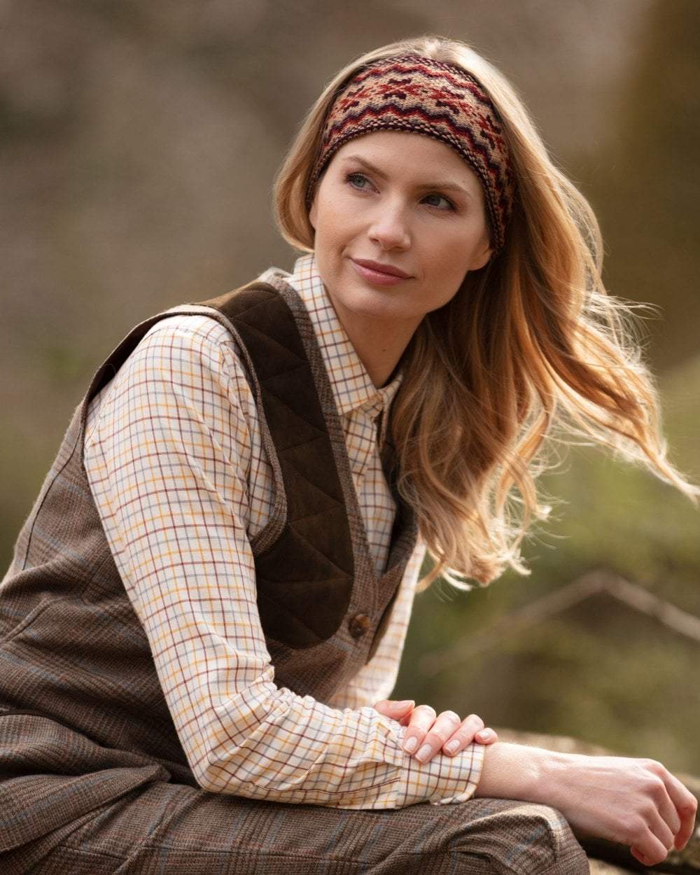 Chestnut coloured House of Cheviot Lady Fairisle Headband on blurry background