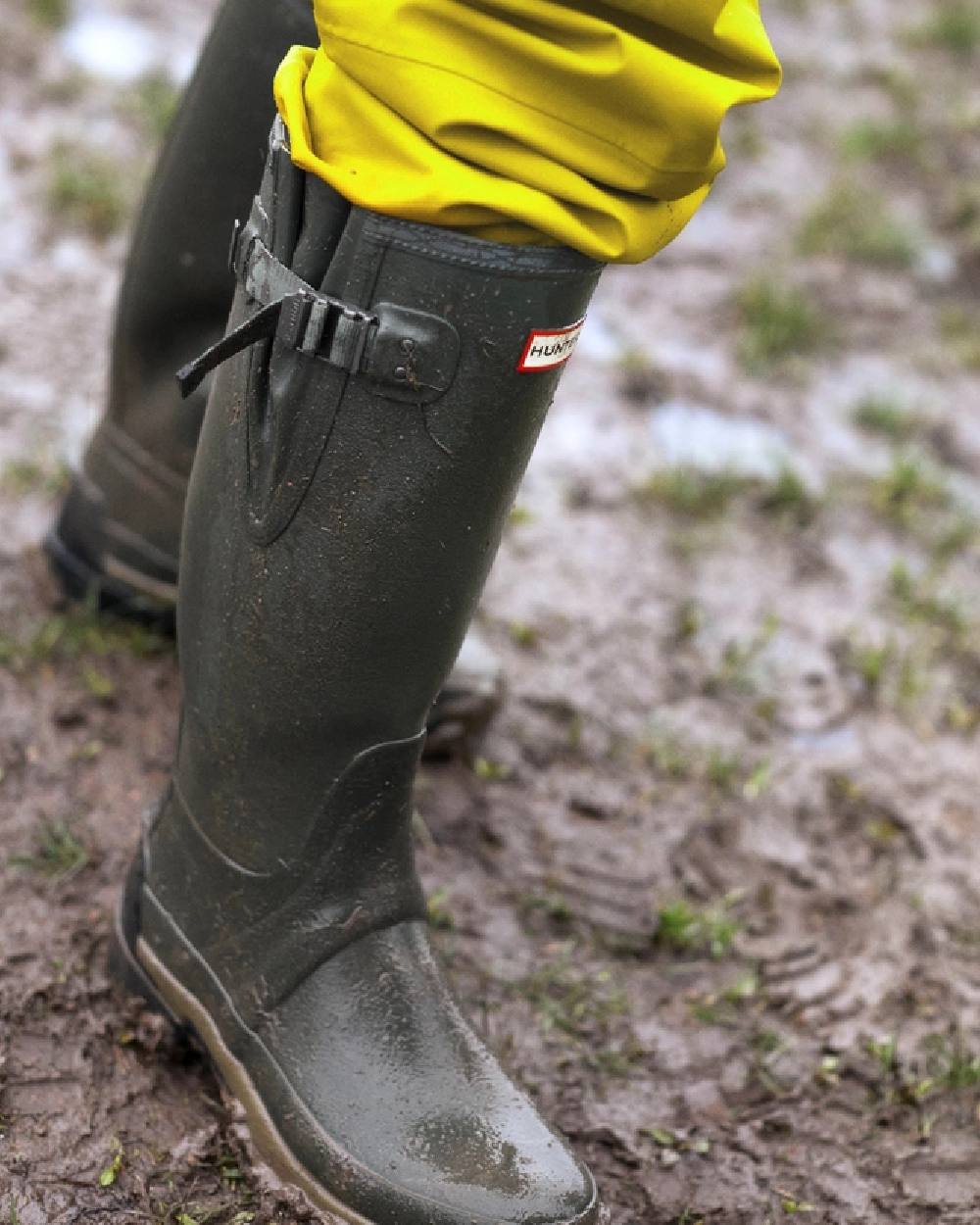 Dark Olive coloured Hunter Mens Balmoral Neoprene Adjustable Wellington Boots on mud background