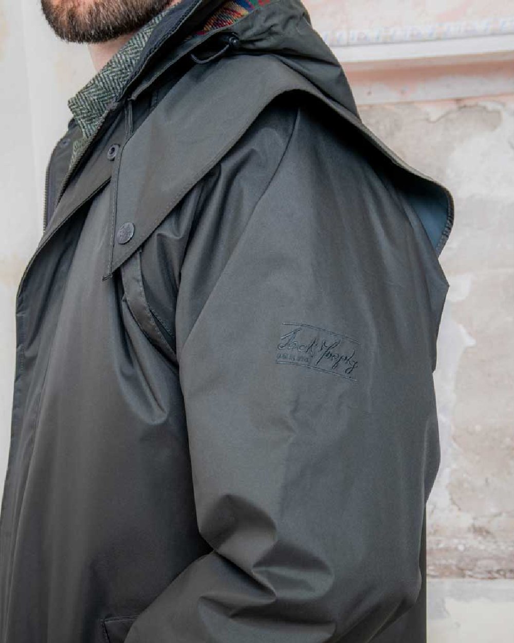 Olive coloured Jack Murphy Lambourne Mens Long Bush Coat on wall background