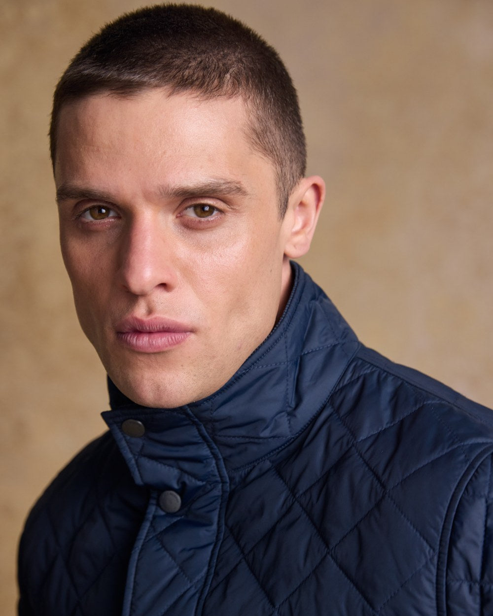 Navy coloured Jack Murphy Ronan Quilted Jacket on wall background