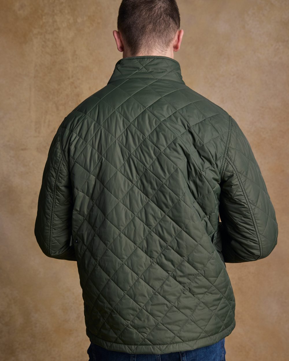 Olive coloured Jack Murphy Ronan Quilted Jacket on wall background