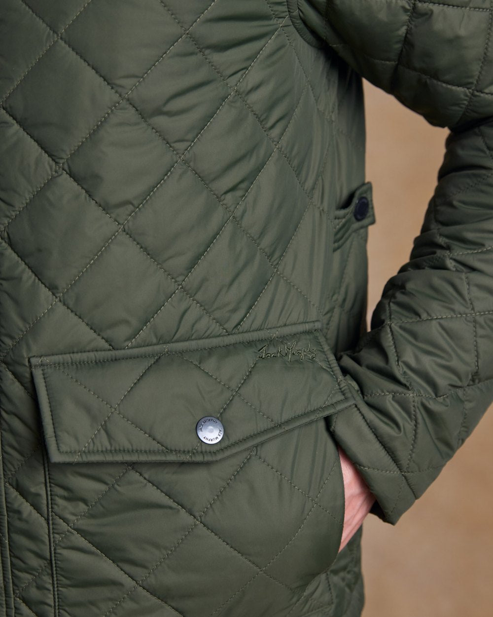 Olive coloured Jack Murphy Ronan Quilted Jacket on wall background