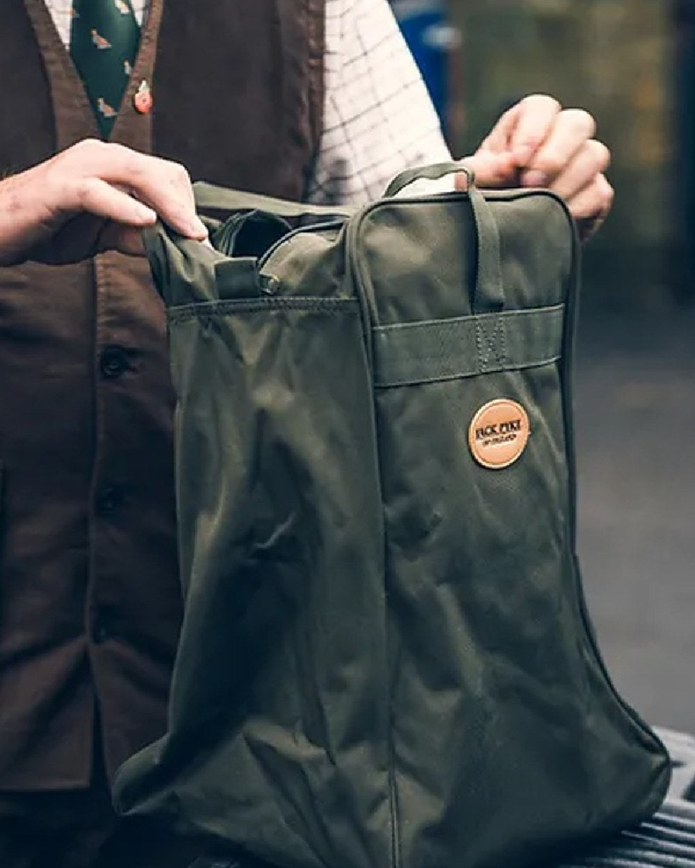 Green coloured Jack Pyke Boot Bag on blurry background