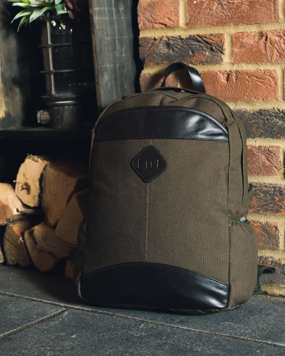 Green coloured Jack Pyke Canvas Field Pack on brick wall background