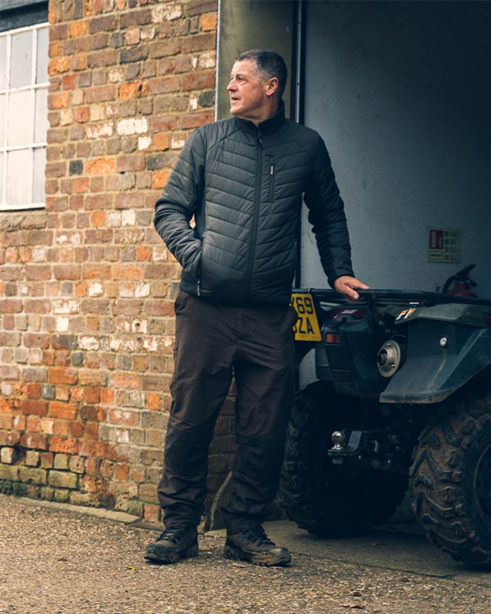 Green coloured Jack Pyke Hybrid Jacket on brick wall background