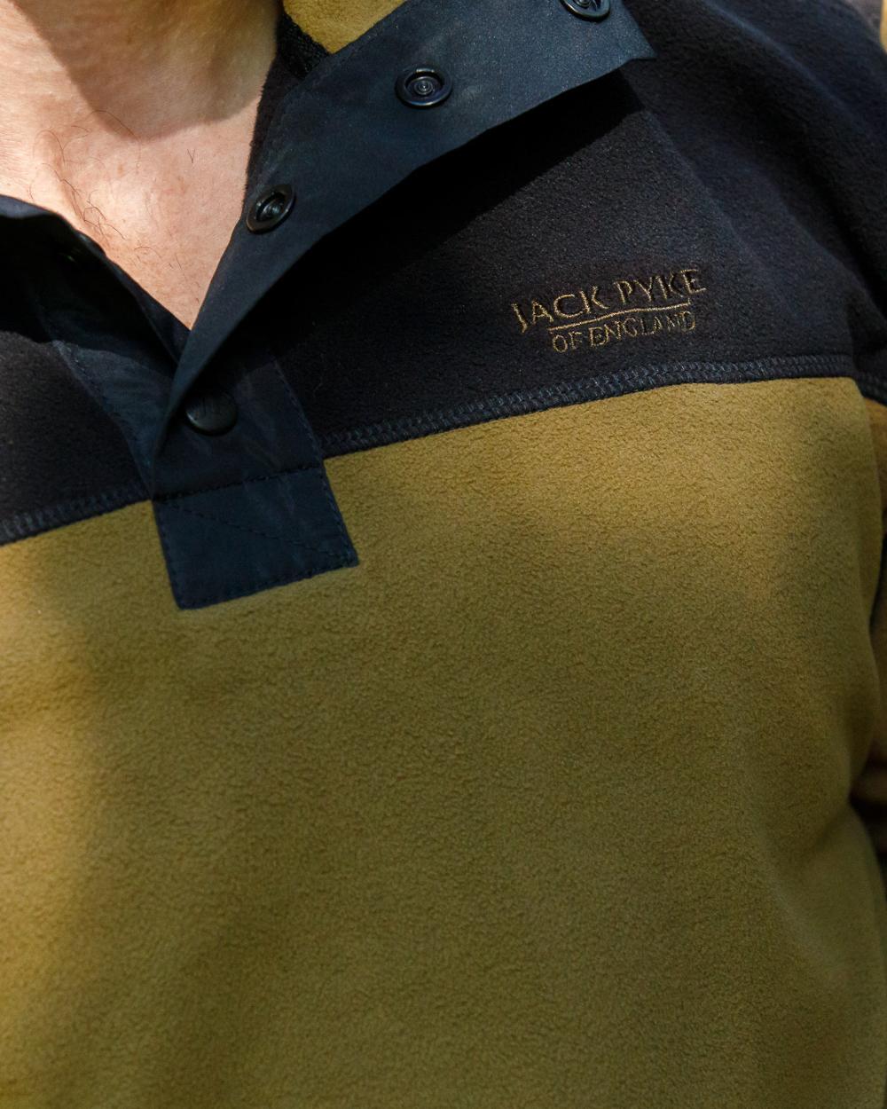 Dark Mustard coloured Jack Pyke Snap Neck Fleece Top on forest Background