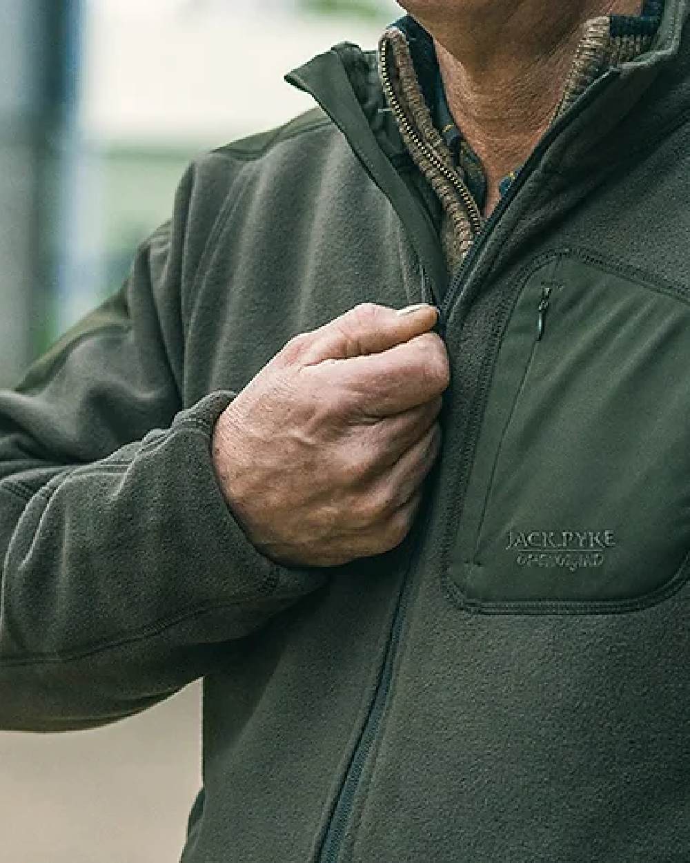 Green coloured Jack Pyke Weardale Fleece Jacket on blurry background