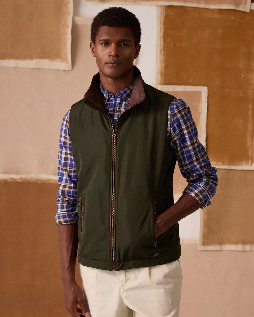 Green coloured Joules Mens Farnham Padded Fleece Lined Gilet on wall background