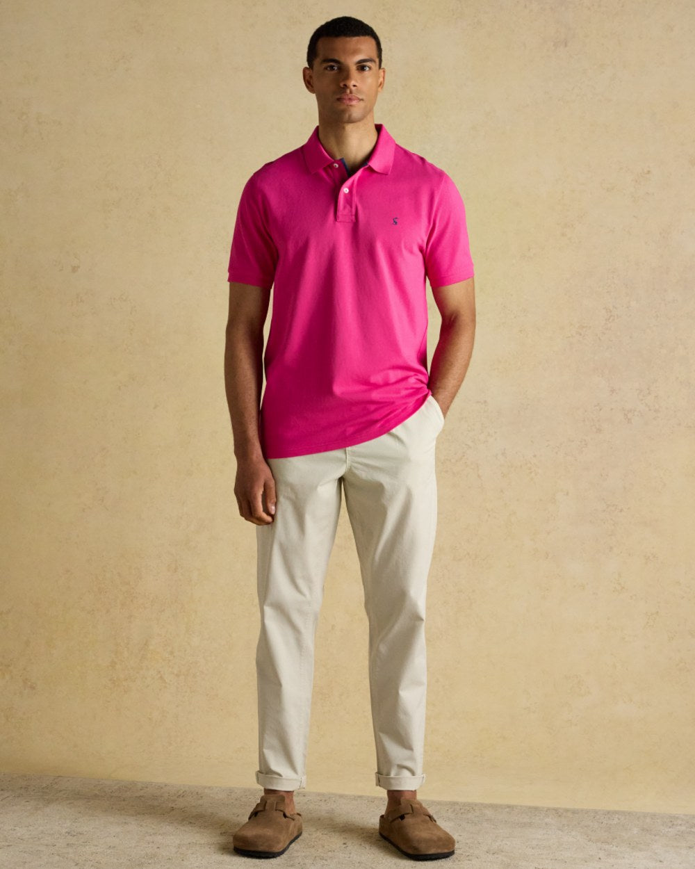 Magenta Pink coloured Joules Mens Woody Cotton Pique Polo Shirt on wall background