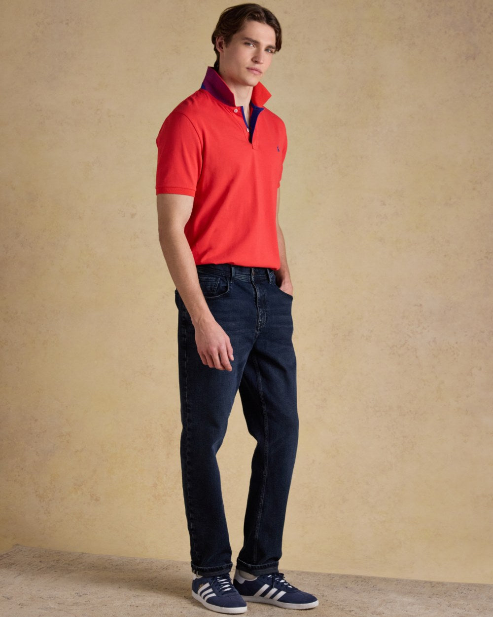Red coloured Joules Mens Woody Cotton Pique Polo Shirt on wall background