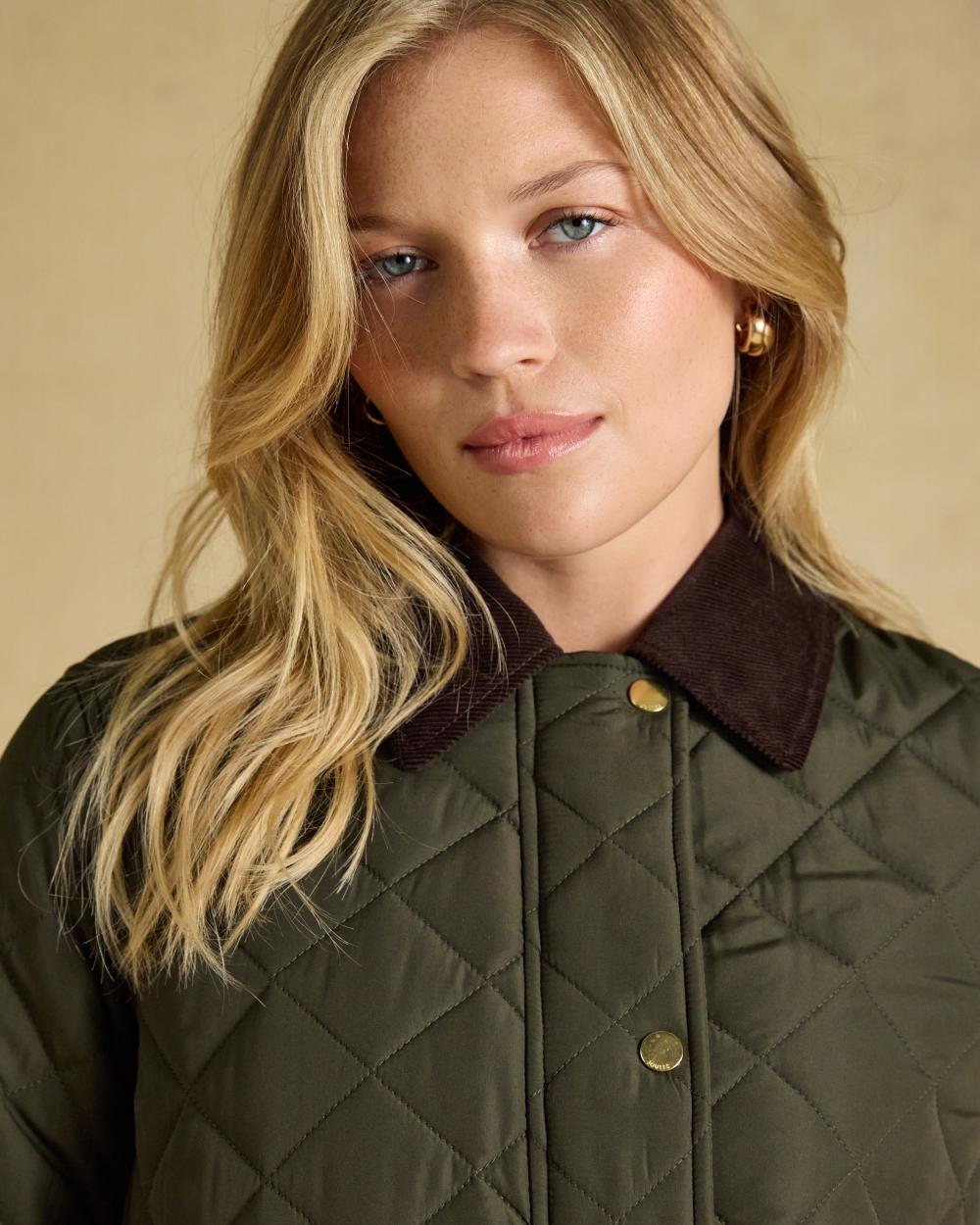Khaki Green coloured Joules Womens Highgrove Diamond Quilted Jacket on beige background