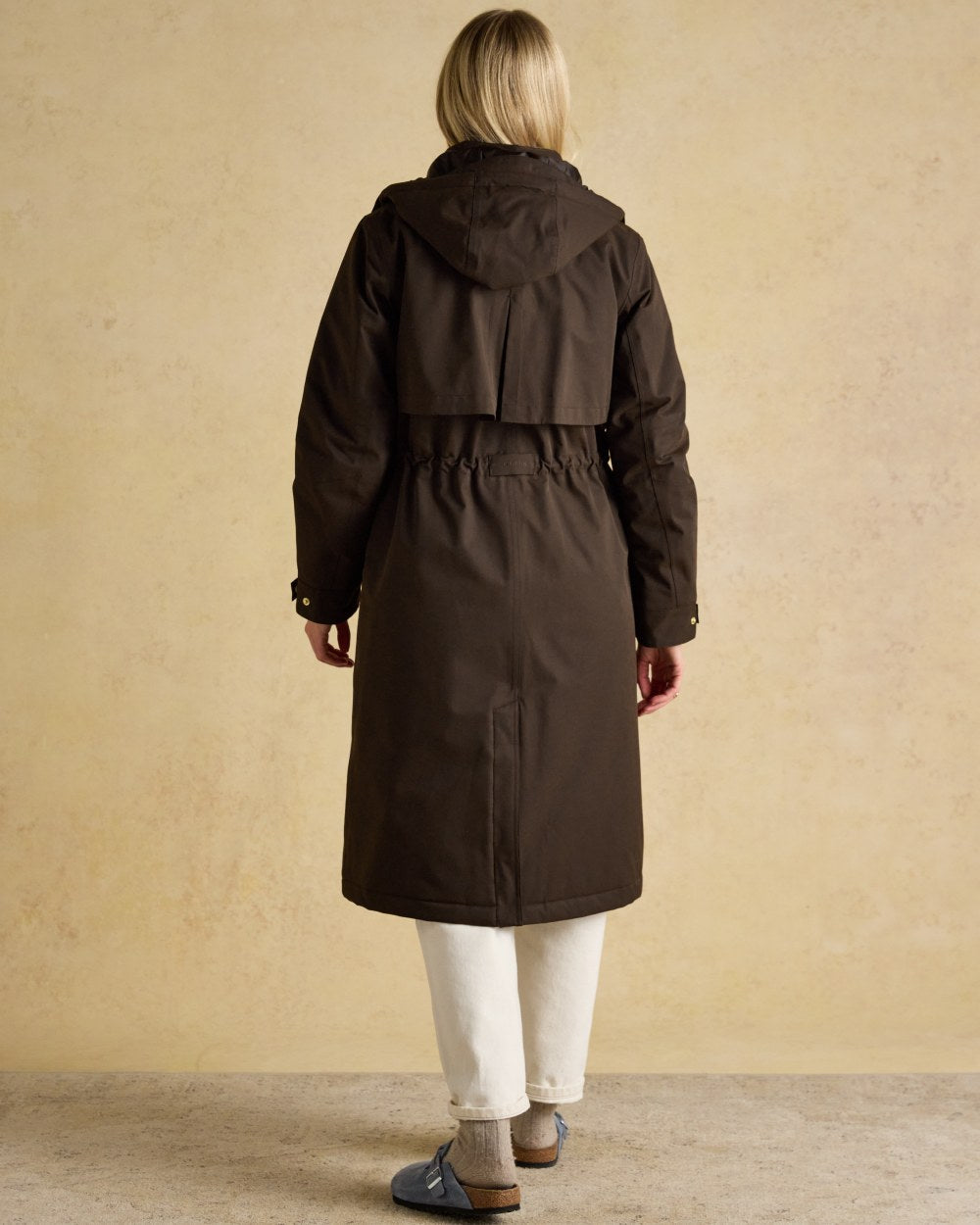Chocolate Brown coloured Joules Womens Warmwell Waterproof Fleece Lined Raincoat on tan background