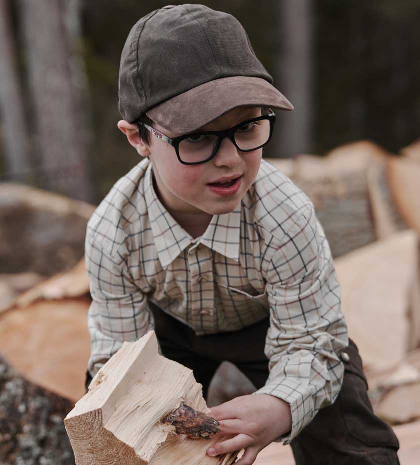 Kids Shirts & Tops - Small boy in tattersall shirt plays with chopped wood.