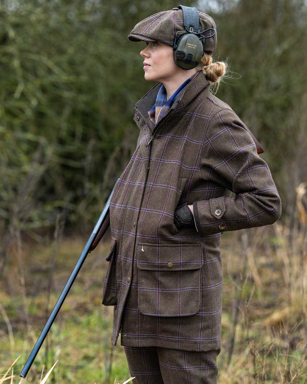 Woman wearing Laksen Pippa Tweed Coat while shooting with mixed trees in background.