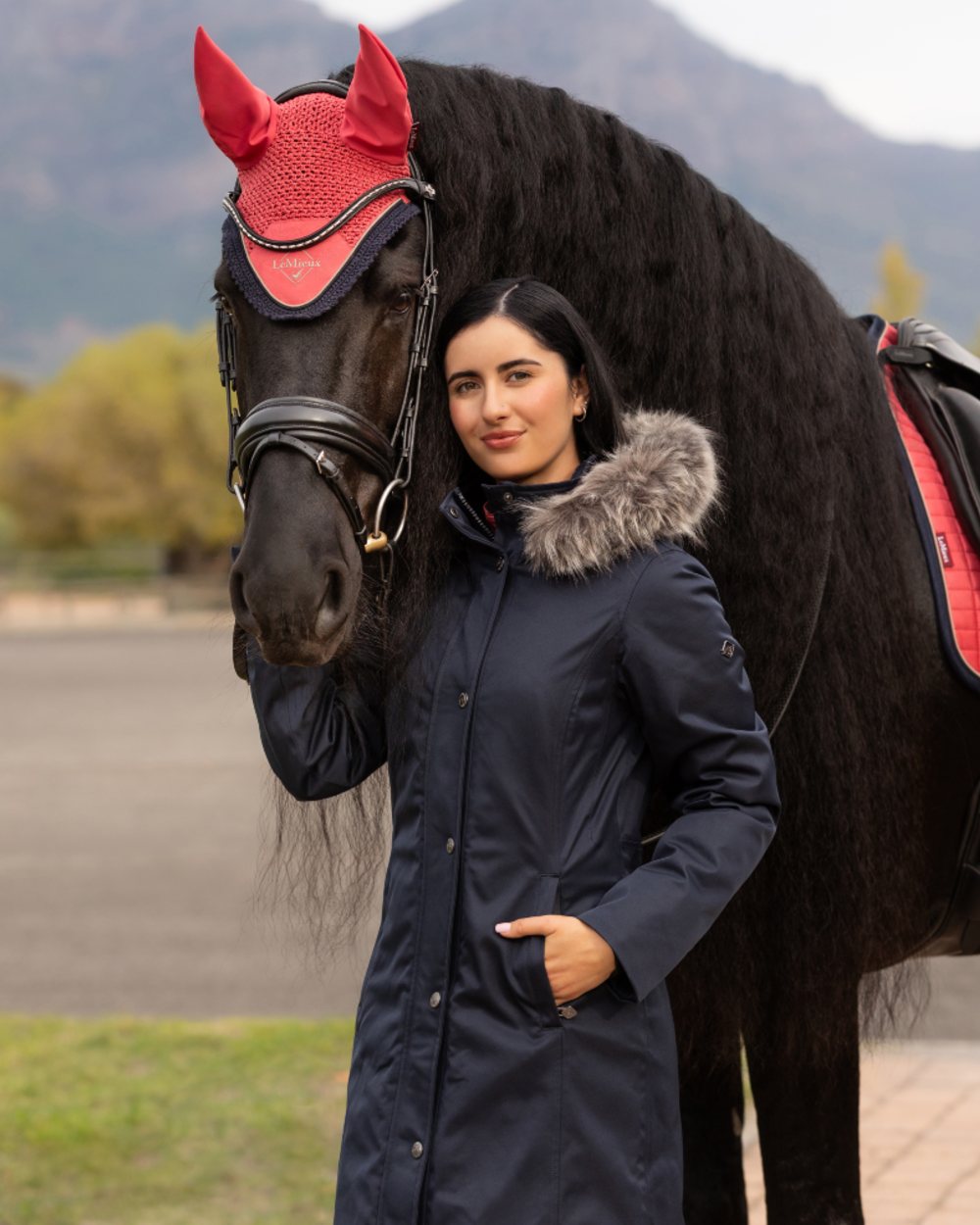 Navy Coloured LeMieux Anya Waterproof Riding Coat On A Mountain Background