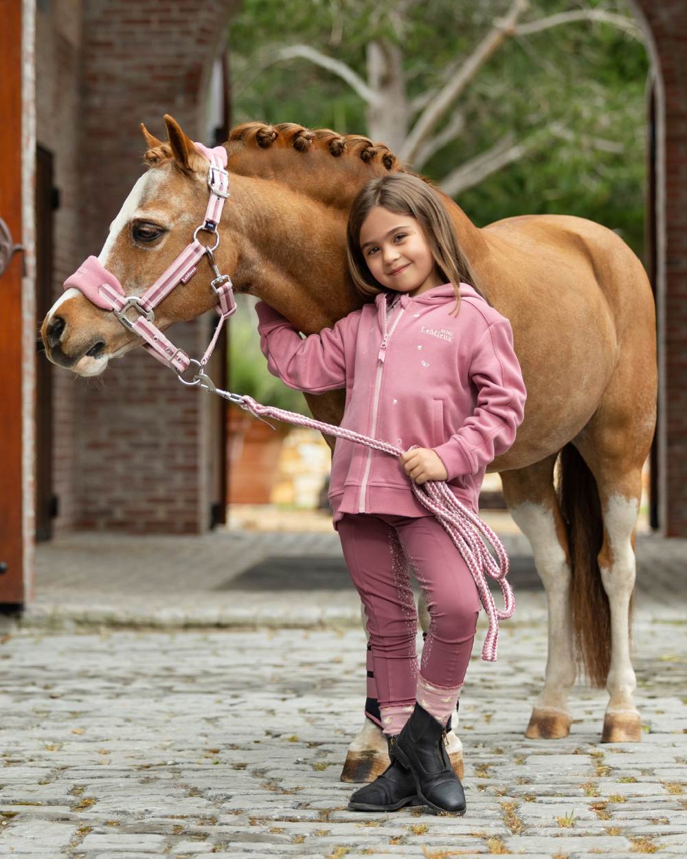 Peony coloured LeMieux Childrens Mini Charlie Zip Through Hoodie on backyard background