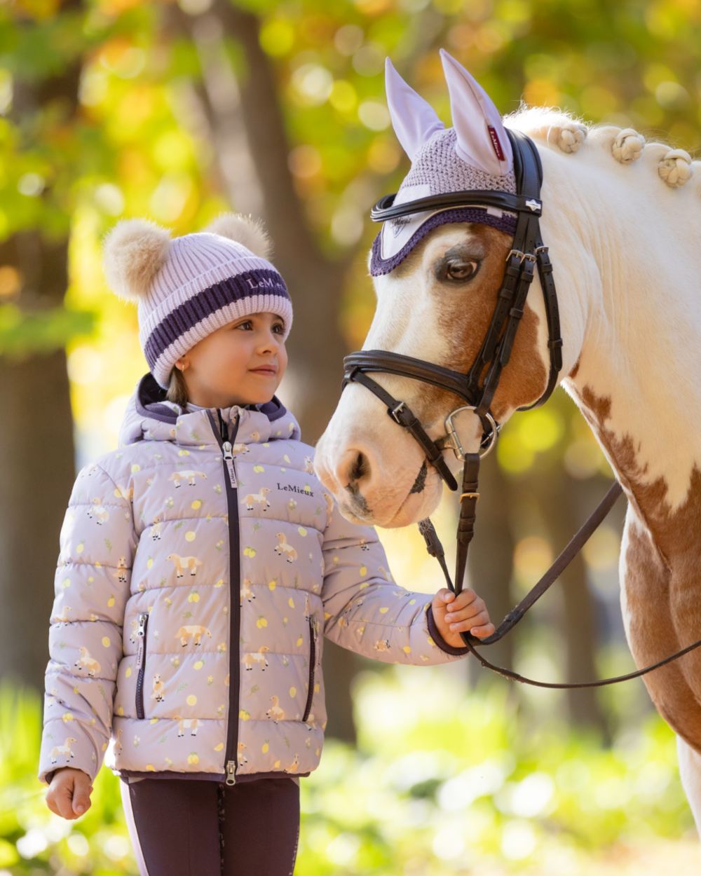 Lilac coloured LeMieux Childrens Mini Printed Lilo Puffer Jacket on tree background