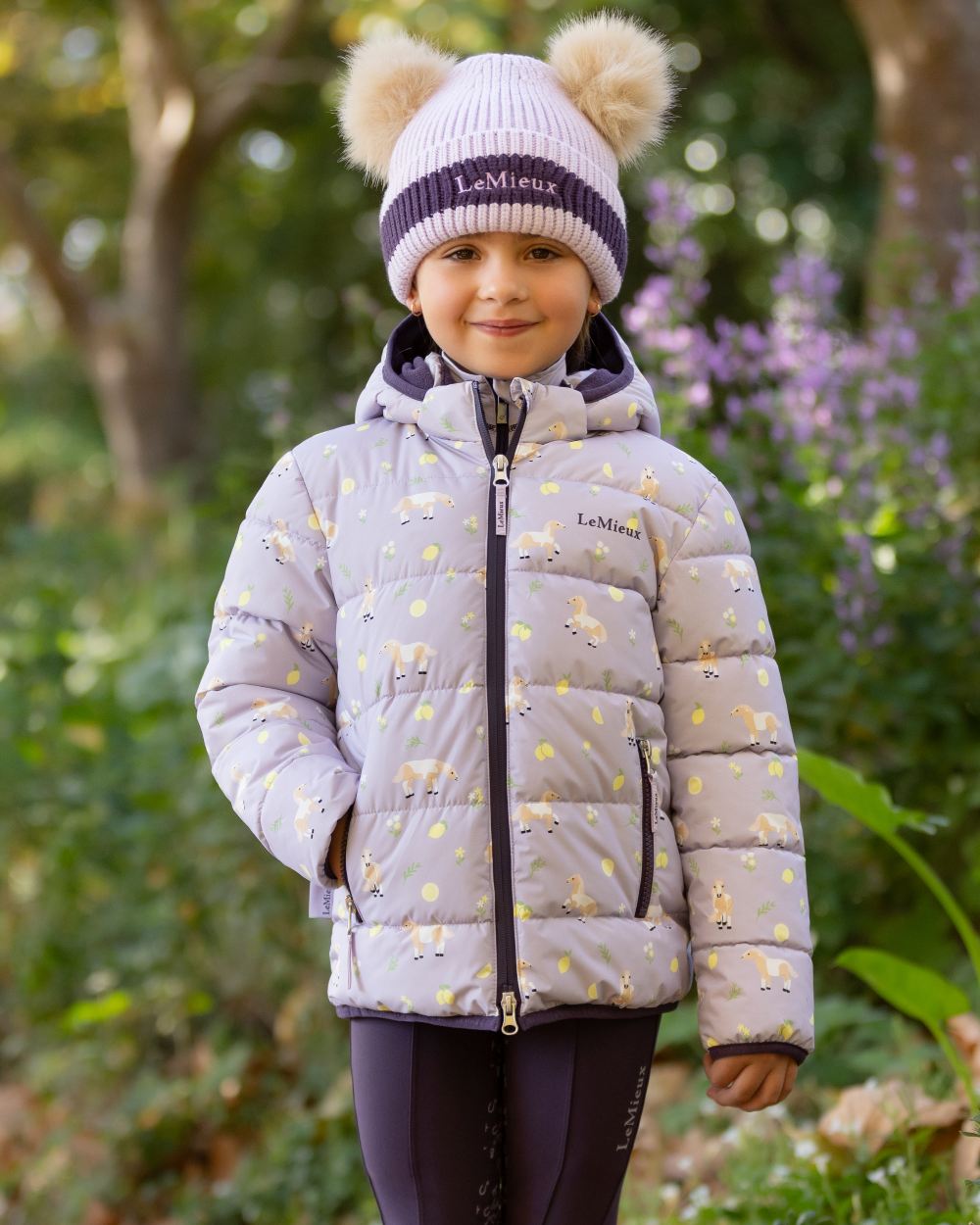 Lilac coloured LeMieux Childrens Mini Printed Lilo Puffer Jacket on tree background