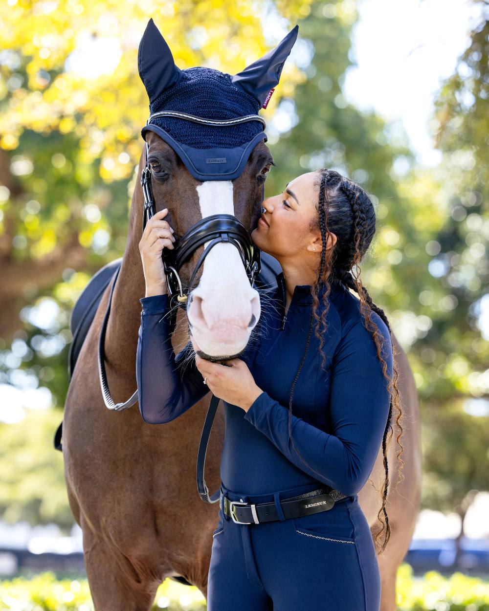 Navy coloured LeMieux Essence Acoustic Fly Hood on blurry background