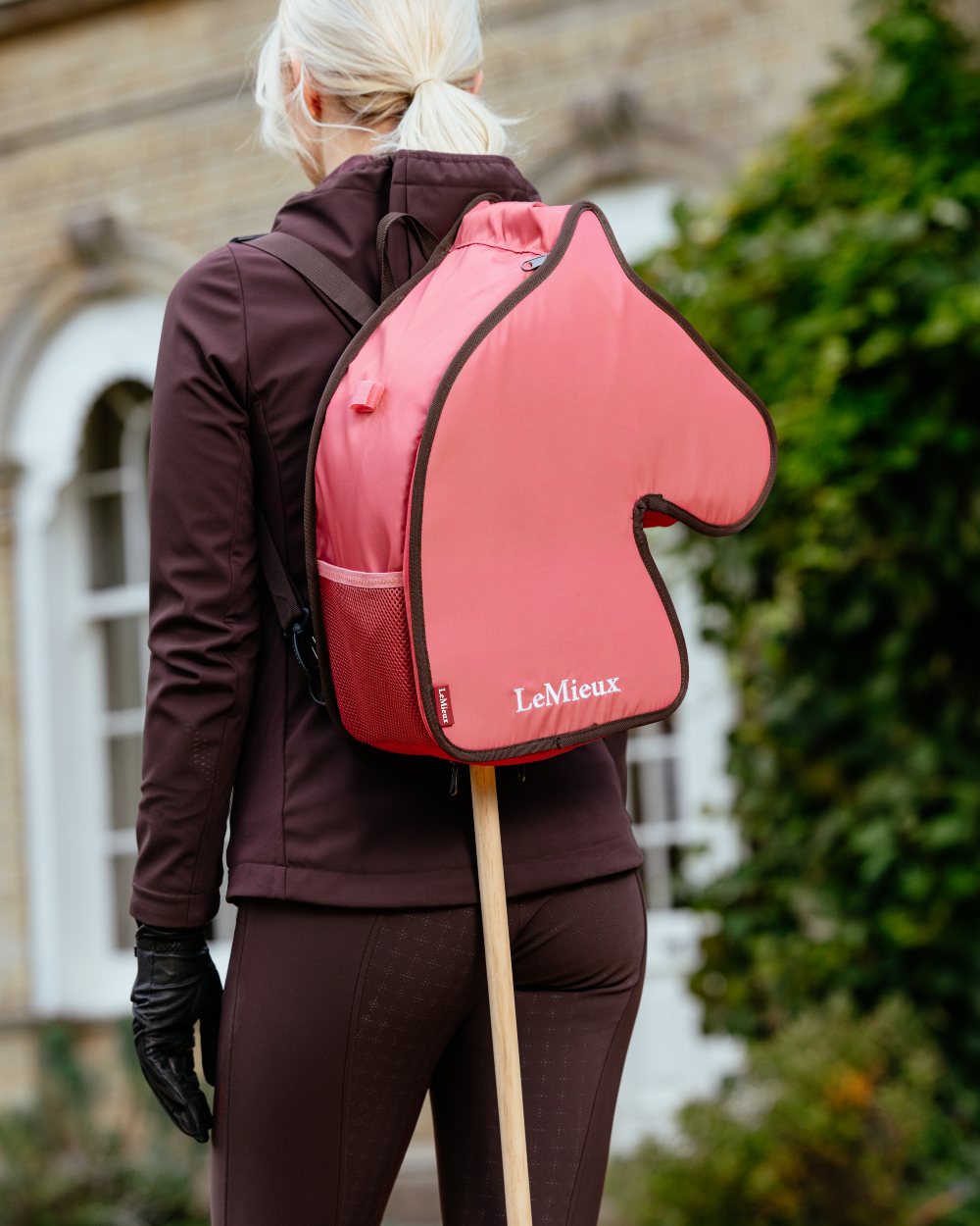 Cranberry coloured LeMieux Hobby Horse Carry Bag on outdoor background