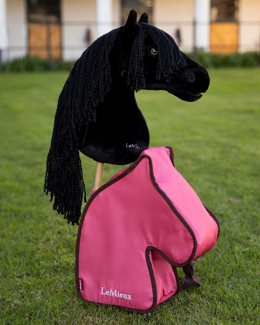 Cranberry coloured LeMieux Hobby Horse Carry Bag on garden background