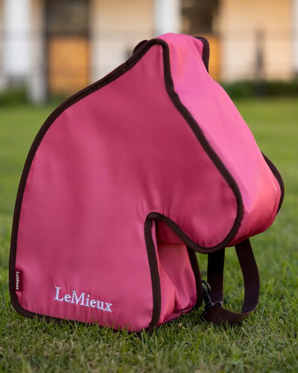 Cranberry coloured LeMieux Hobby Horse Carry Bag on garden background