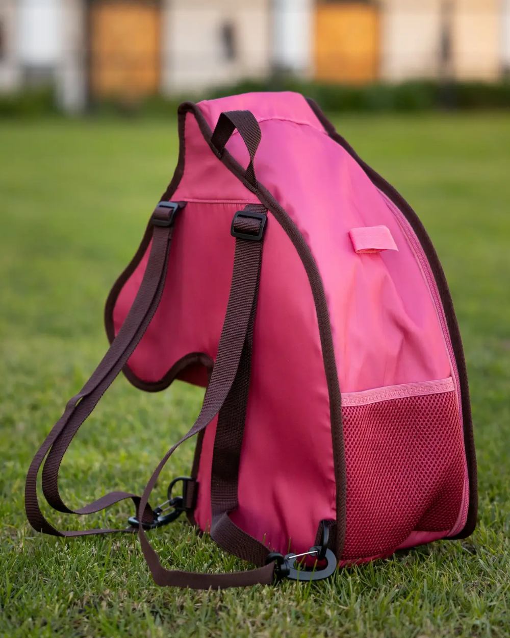 Cranberry coloured LeMieux Hobby Horse Carry Bag on garden background