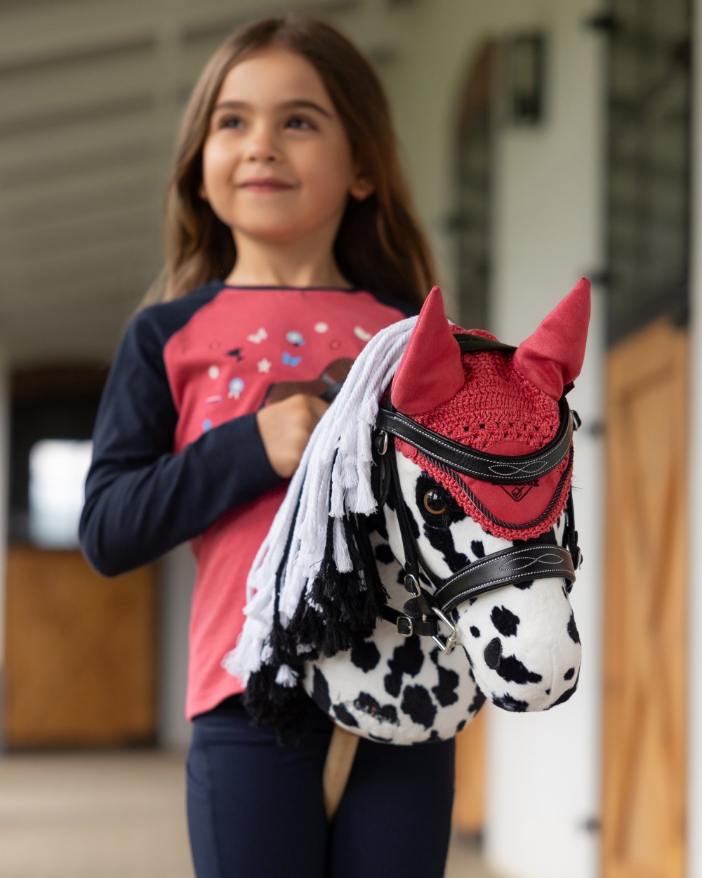 Cranberry coloured LeMieux Hobby Horse Fly Hood on outdoor background