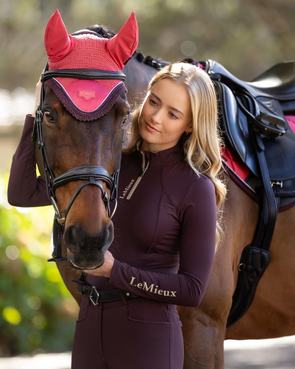 Cranberry coloured LeMieux Loire Fly Hood on blurry background