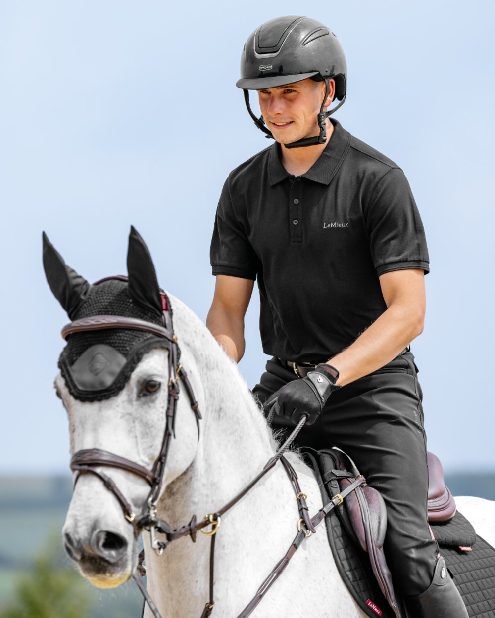 Black coloured LeMieux Mens Classique Polo T-Shirt on sky background