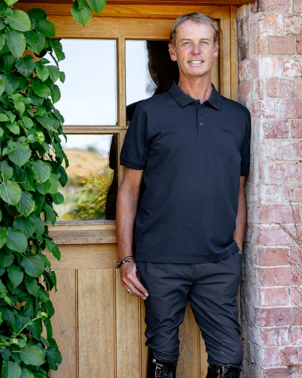 Black coloured LeMieux Mens Classique Polo T-Shirt on outdoor background