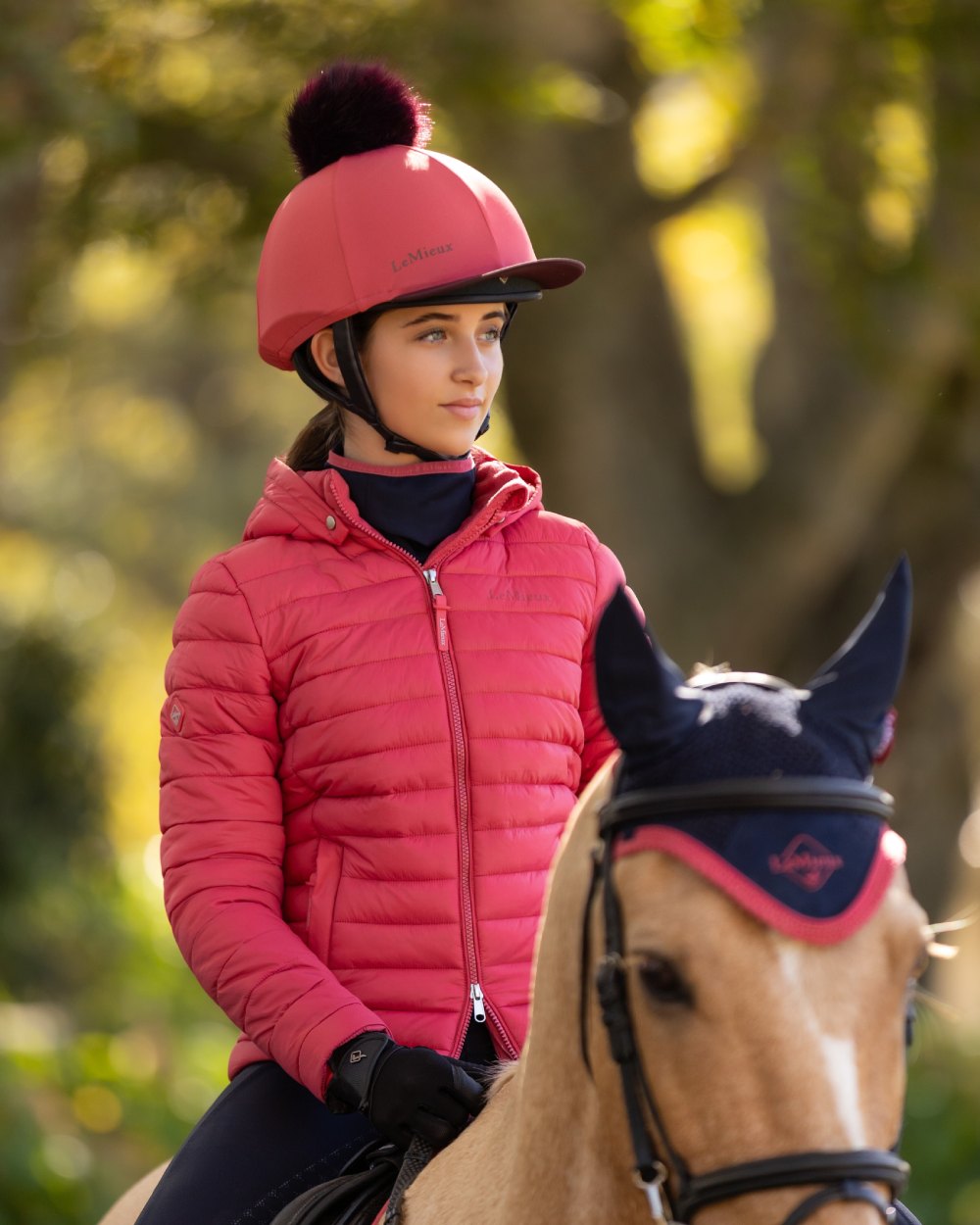 Cranberry coloured LeMieux Classique Pom Hat Silk on blurry background