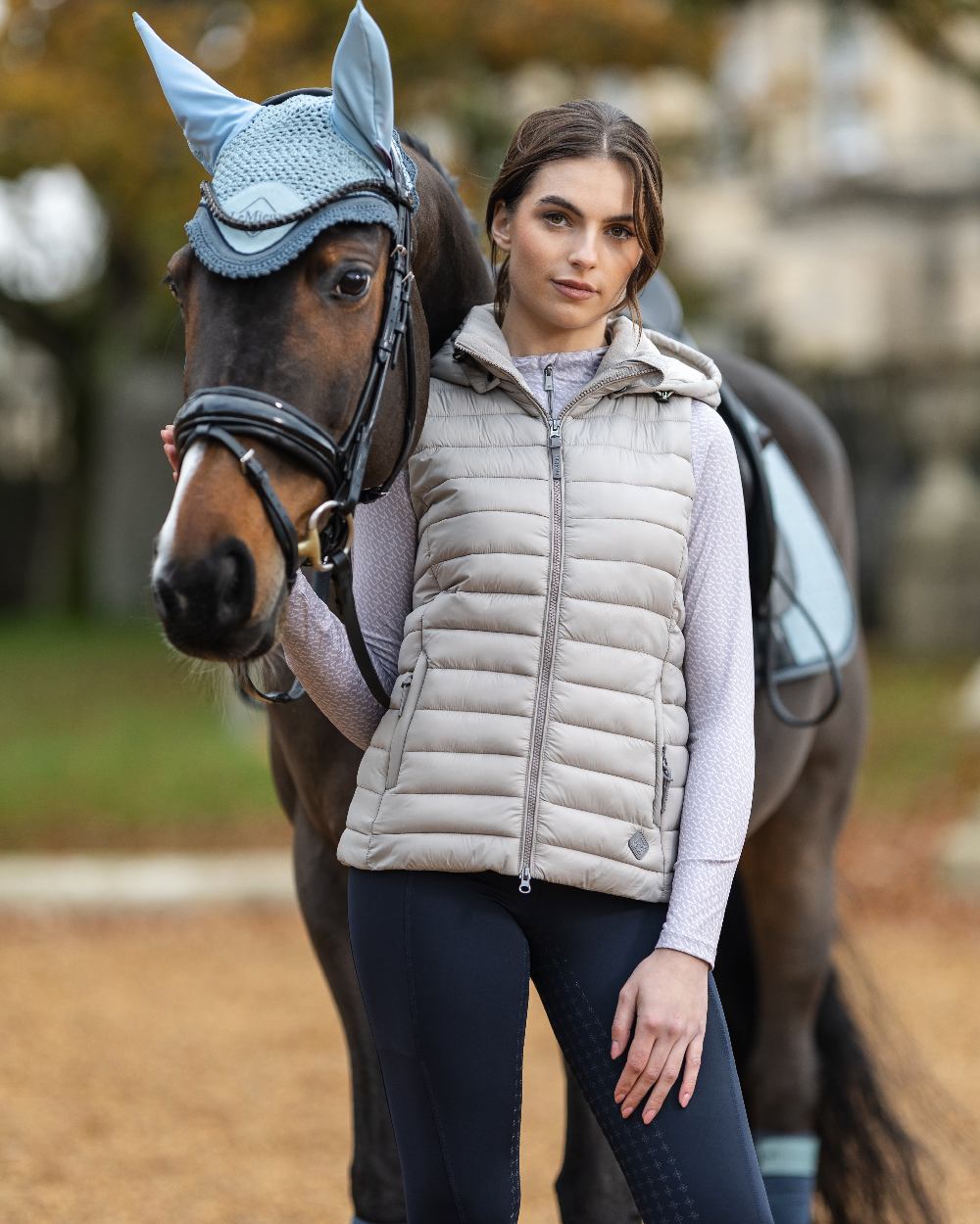 Ash coloured LeMieux Tilly Hooded Puffer Gilet on blurry background
