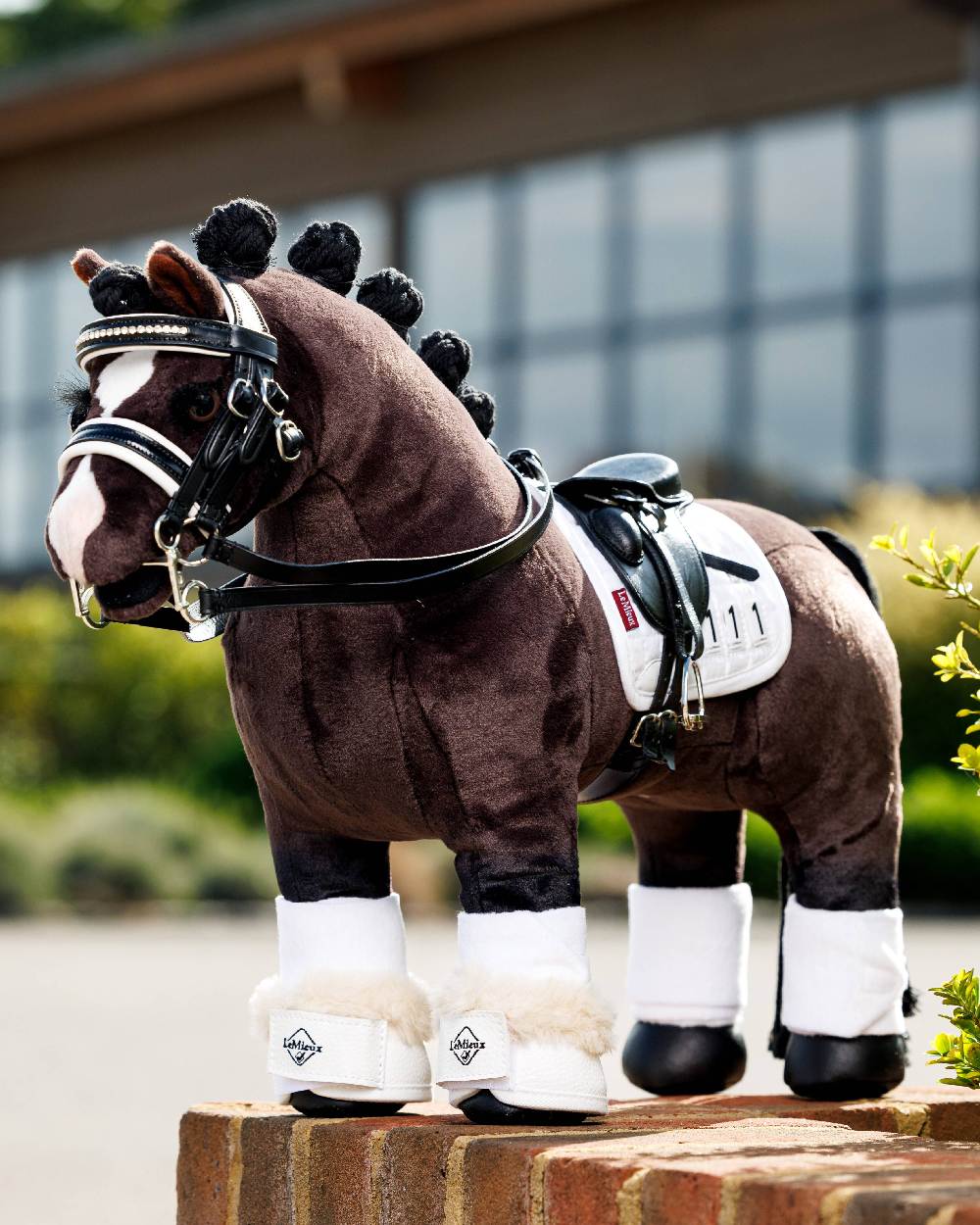 White coloured LeMieux Toy Pony Dressage Over Reach Boot on blurry background
