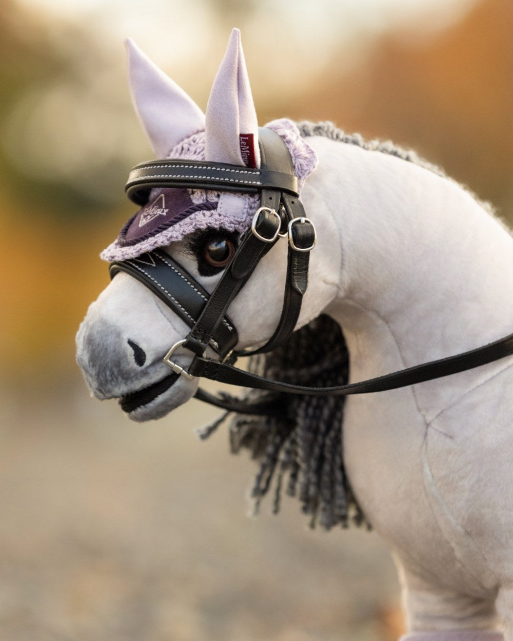 Lilac coloured LeMieux Toy Pony Fly Hood on blurry background