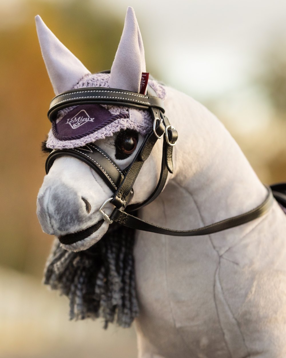 Lilac coloured LeMieux Toy Pony Fly Hood on blurry background