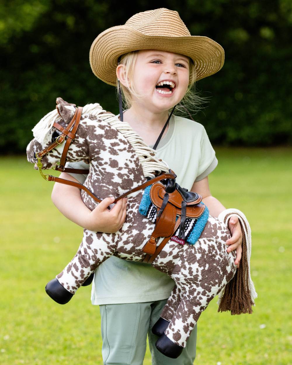 Tan coloured LeMieux Toy Pony Western Bridle on blurry green background