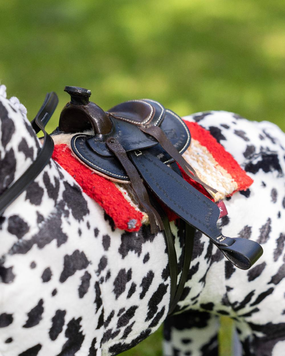 Black coloured LeMieux Toy Pony Western Saddle on blurry green background