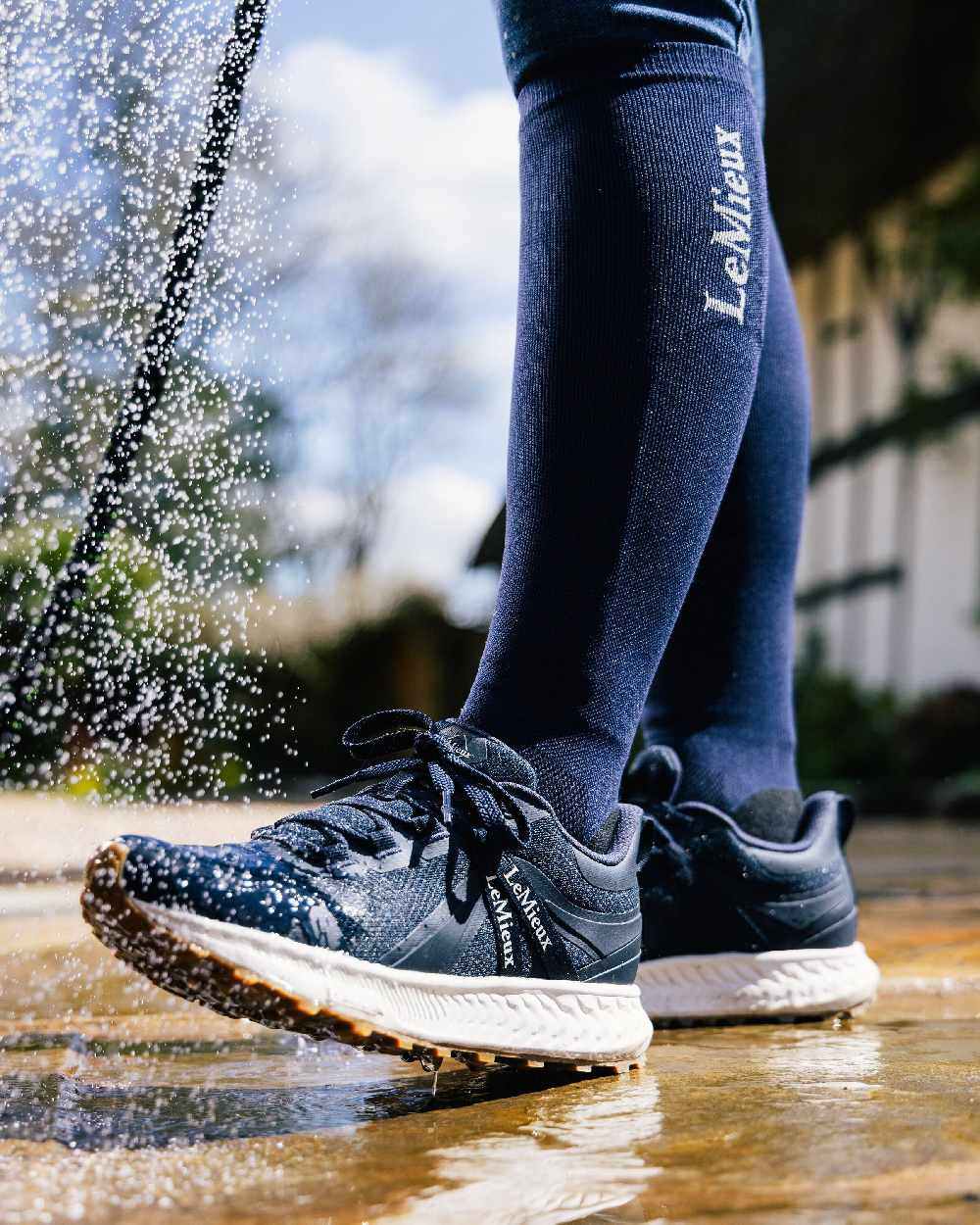 Navy coloured LeMieux Trax Waterproof Trainers on blurry background