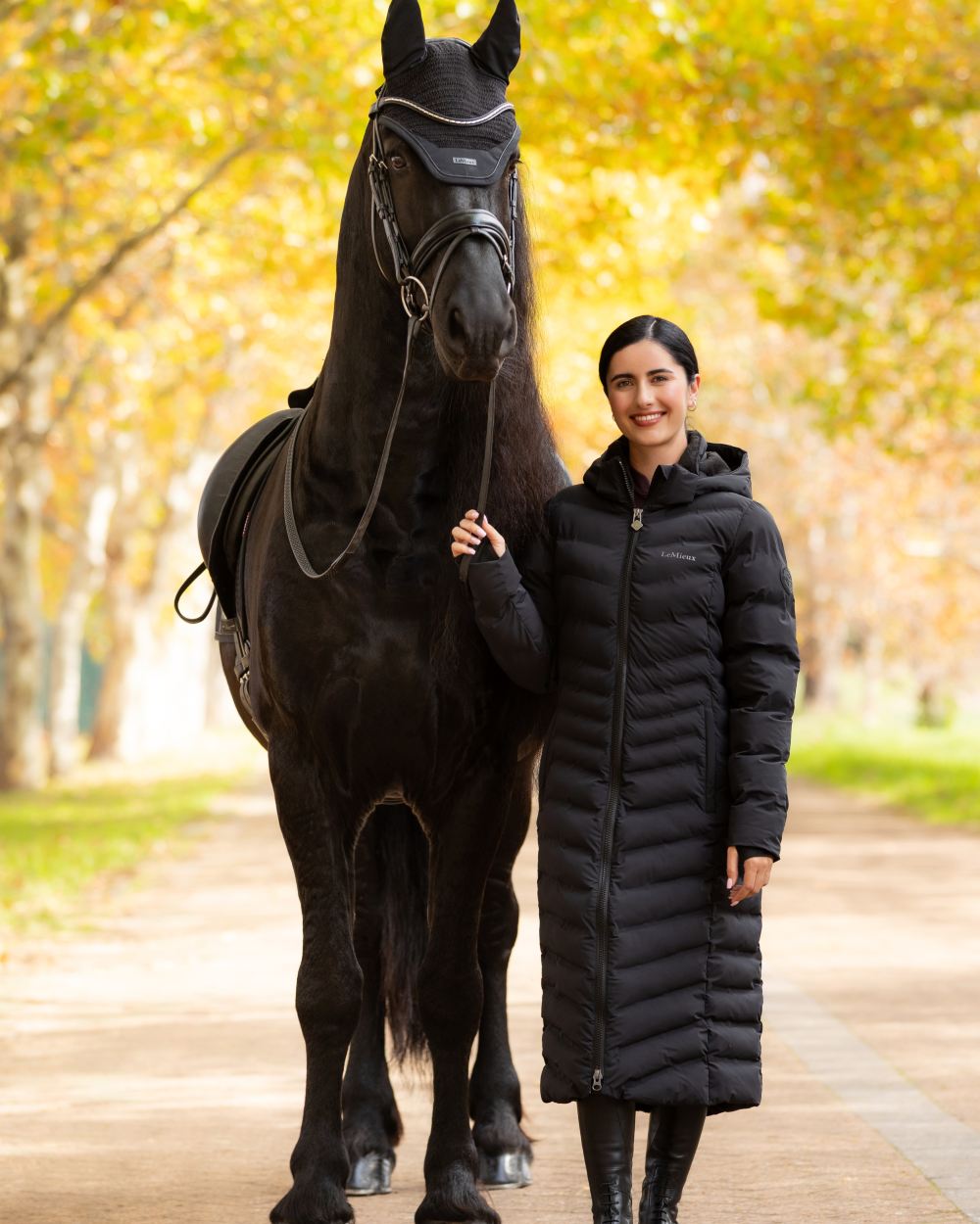 Black coloured LeMieux Womens Hayley Water Resistant Longline Puffer Coat on tree background