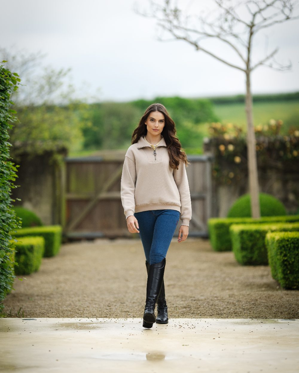 Almond coloured LeMieux Womens Keira Quarter Neck Sweatshirt on backyard background