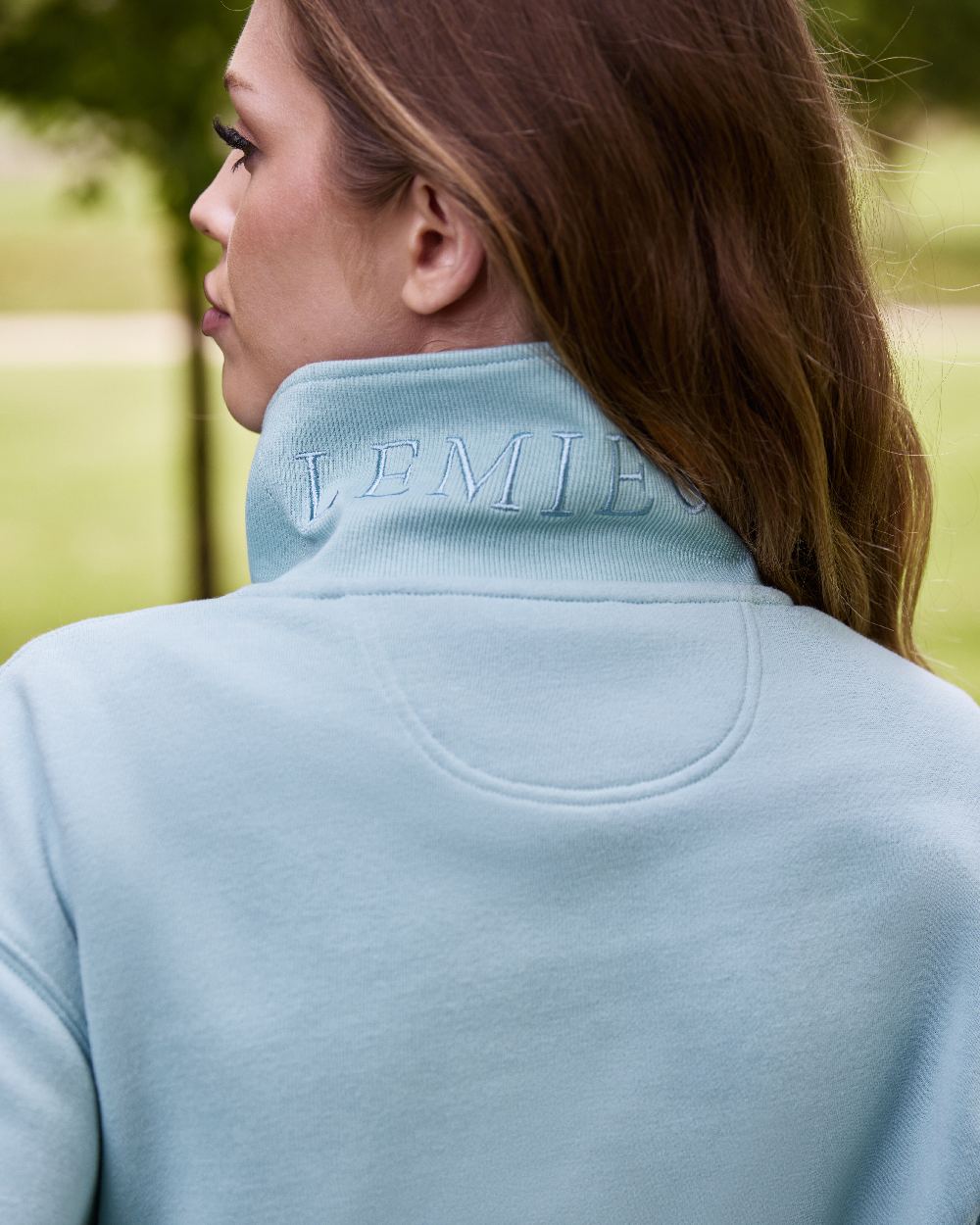 Aqua coloured LeMieux Womens Keira Quarter Neck Sweatshirt on blurry background