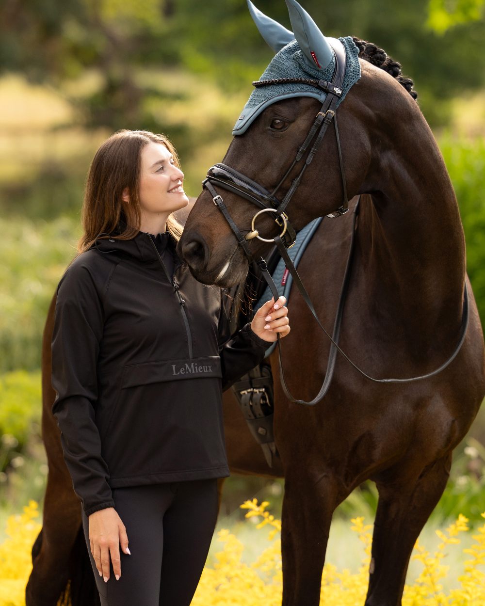 Black coloured LeMieux Womens Perri Half Zip Waterproof Jacket on tree background