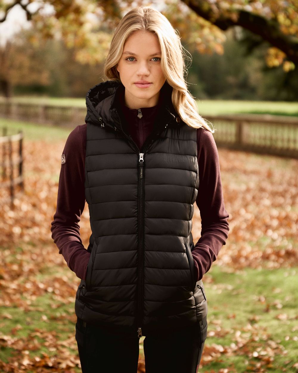 Black coloured LeMieux Womens Rose Hooded Puffer Gilet on outdoor background